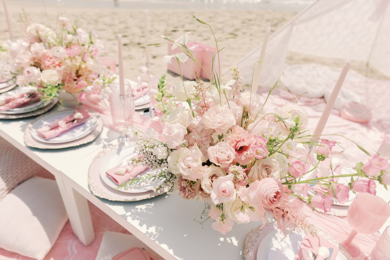 A lush blush and ivory rose centerpiece over a set table