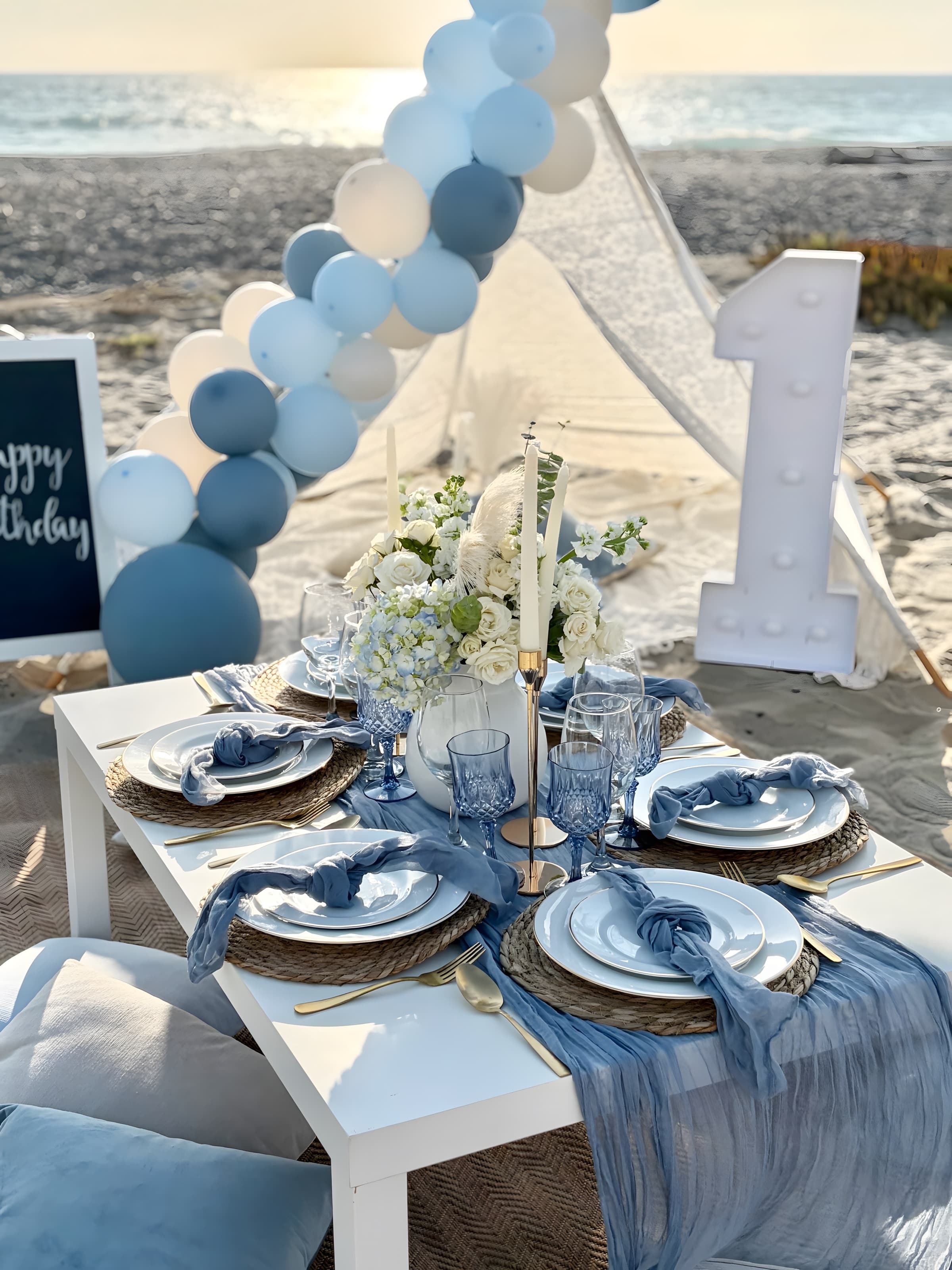 A low view down a dusty-blue birthday table with a blue gauze runner, hydrangeas and taper candles